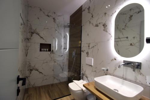 a bathroom with a sink and a toilet and a mirror at Hotel Beach Restaurant Fabio in Borsh
