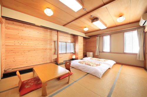 1 dormitorio con 1 cama y pared de madera en Fujinomiya Green Hotel, en Fujinomiya