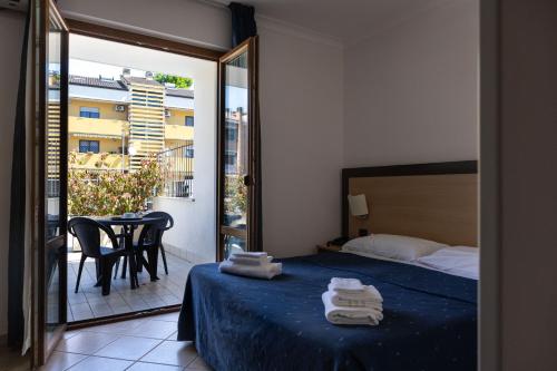 a bedroom with a bed and a balcony with a table at Hotel La Quercia in Valmontone