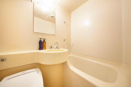 a bathroom with a sink and a tub and a toilet at Fujinomiya Green Hotel in Fujinomiya