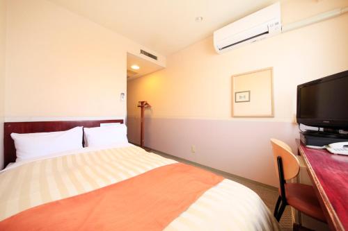 a hotel room with a bed and a flat screen tv at Fujinomiya Green Hotel in Fujinomiya