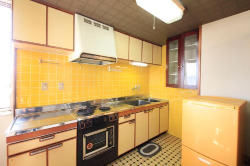 a yellow tiled kitchen with a stove and a sink at Fujinomiya Green Hotel in Fujinomiya