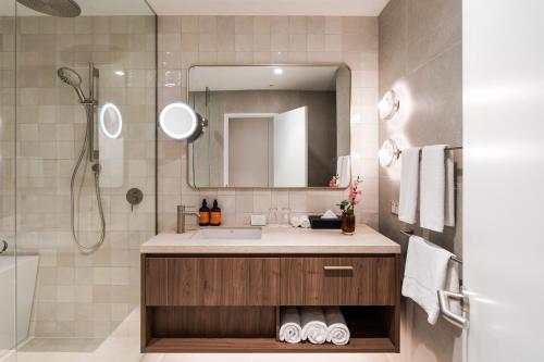 a bathroom with a sink and a shower with a mirror at Amora Herencia Riverwalk Melbourne in Melbourne