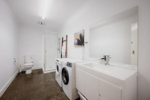 a white bathroom with a washing machine and a sink at Ruby SoHo Workshop Villa in Port Sorell