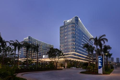 a tall building with palm trees in front of it at Aloft by Marriott Xiamen Xiangan in Xiamen