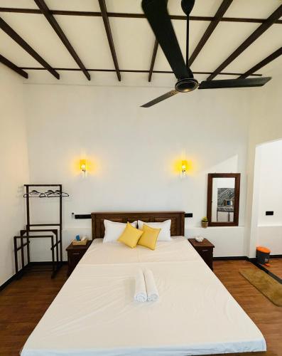 a bedroom with a bed with white sheets and yellow pillows at Earthora Escape in Dickwella