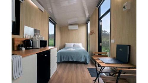 a room with a bed and a desk with a laptop at Churinga Orchards by Tiny Away in Lenswood