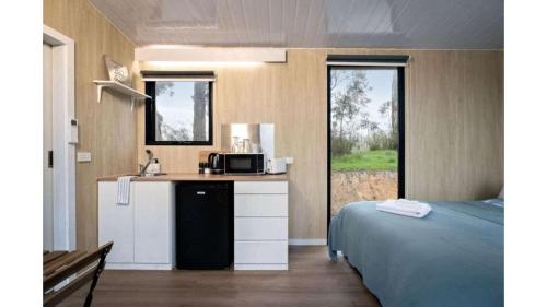 a room with a bed and a kitchen with a microwave at Churinga Orchards by Tiny Away in Lenswood