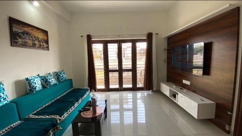 a living room with a blue couch and a tv at Vayangankar House in Belgaum