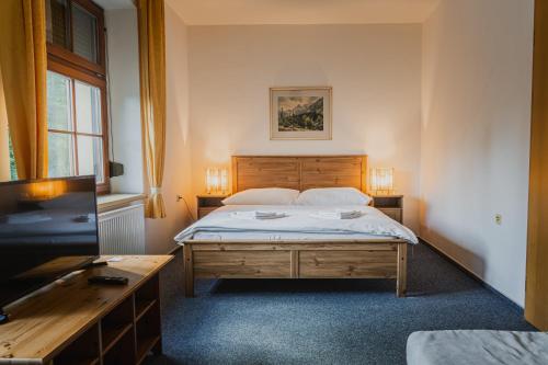 a bedroom with a bed and a flat screen tv at Hotel Růžové údolí in Pivonín