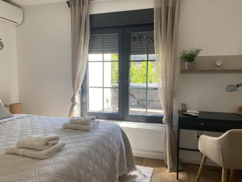 a bedroom with a bed and a window with towels on it at Petite Mansion in Našice