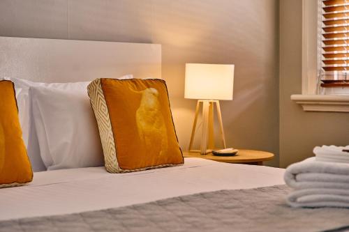 a bed with an orange pillow and a lamp at Healesville Hotel in Healesville