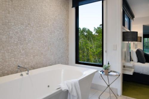 a white bath tub in a bathroom with a window at Saltus One bedroom- luxury and panoramic views in Hepburn Springs