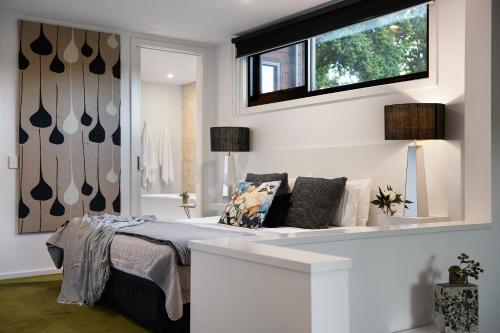 a white bedroom with a bed and a window at Saltus One bedroom- luxury and panoramic views in Hepburn Springs