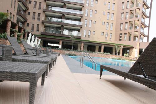 a row of benches next to a swimming pool at Speke Apartments Wampewo in Kampala