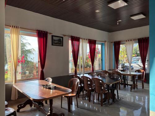 a dining room with tables and chairs and windows at Hotel Chandra Paradise in Munsyari