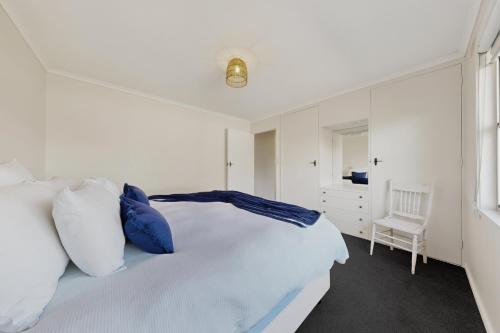 a white bedroom with a bed and a chair at Charming Guesthouse in Kyneton in Kyneton