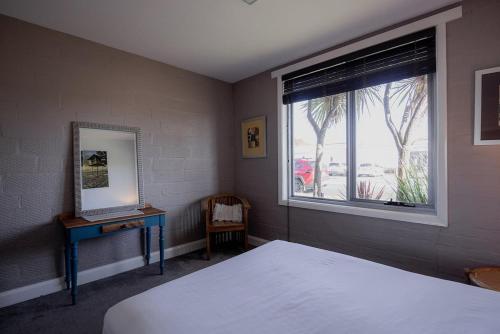 a bedroom with a bed and a window and a desk at Ruby SoHo Spa Villa in Port Sorell