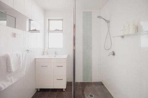 a white bathroom with a shower and a sink at Ruby SoHo Spa Villa in Port Sorell