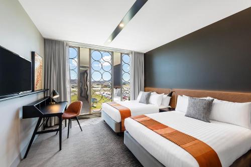a hotel room with two beds and a television at Vibe Hotel Canberra in Canberra