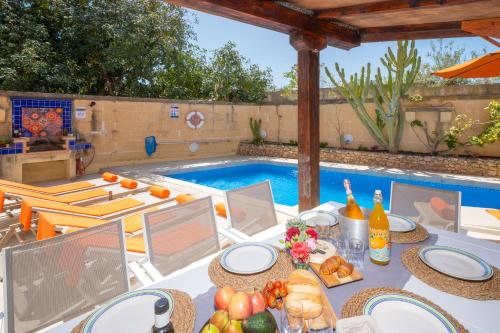 a table with plates of food next to a swimming pool at Il-Mohba Holiday Home in Munxar