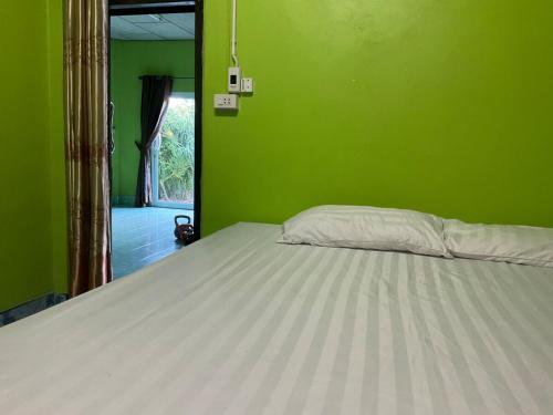 a bedroom with a white bed in a green wall at Khwaeng Phao Beech Poolvilla in Ban Thung Khanan