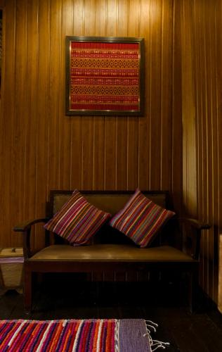 a wooden wall with a bench with two pillows at Baan Phraya Suren บ้านพระยาสุเรนทร์ in Ban Thab Mak