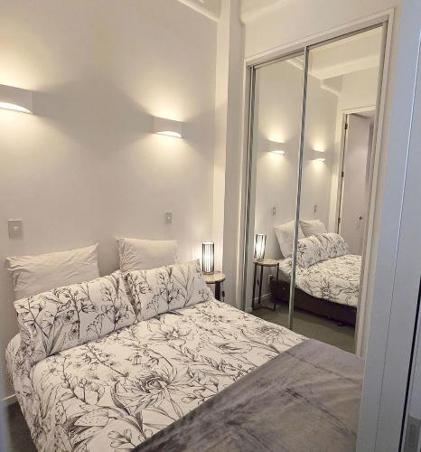 a bedroom with a large bed and a mirror at Art Deco Chic on Queen in Auckland