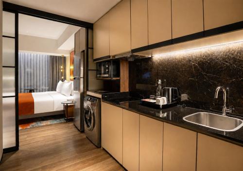 a kitchen with a sink and a room with a bed at Herloom Hotel & Residence BSD Tangerang in Tangerang