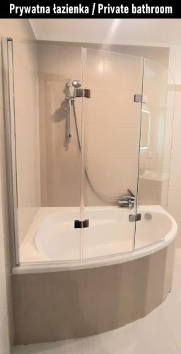 a bath tub with a glass enclosure in a bathroom at Stacja Jeżyce Pokój #B in Poznań
