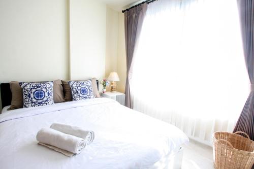 a bedroom with a white bed with towels on it at D Condo Sign Chiang Mai R628 in Chiang Mai