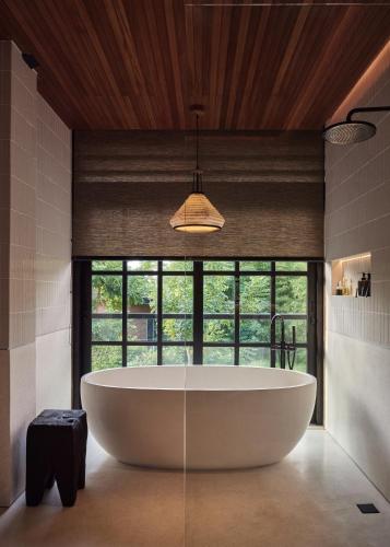 a large bath tub in a bathroom with a large window at Villa Suki in Canggu