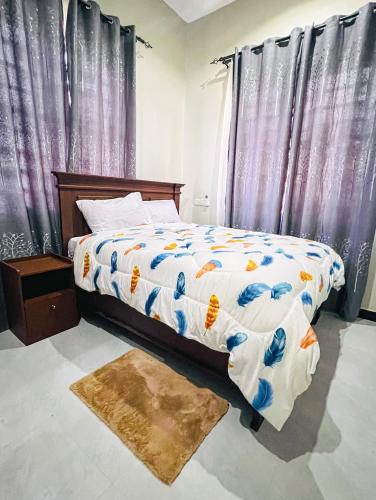 a bedroom with a bed and curtains and a rug at SINDOM APARTMENTS Dodoma in Dodoma