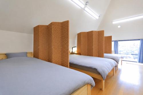 a room with three beds and a window at Hostel FIVE ホステルファイブ in Kochi