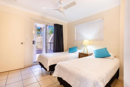 two beds in a room with a window at Eight, Villa Mar Colina in Yeppoon