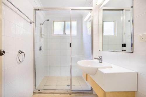 a white bathroom with a shower and a sink at Eight, Villa Mar Colina in Yeppoon