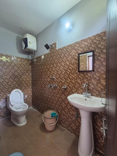 ein Badezimmer mit Toilette, Waschbecken und Spiegel in der Unterkunft Devom Guest House in Phata