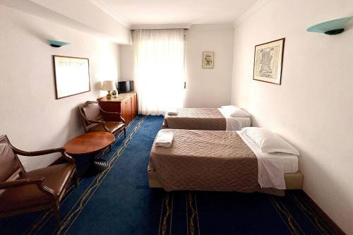 ein Hotelzimmer mit zwei Betten, einem Tisch und Stühlen in der Unterkunft Quality Hotel Nova Domus in Rom