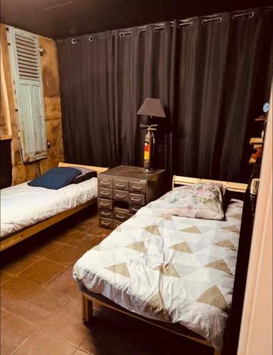 a bedroom with two beds and a table with a lamp at La Mariefacture - Comme au Garage in Laning