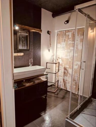 a bathroom with a sink and a glass shower at La Mariefacture - Comme au Garage in Laning