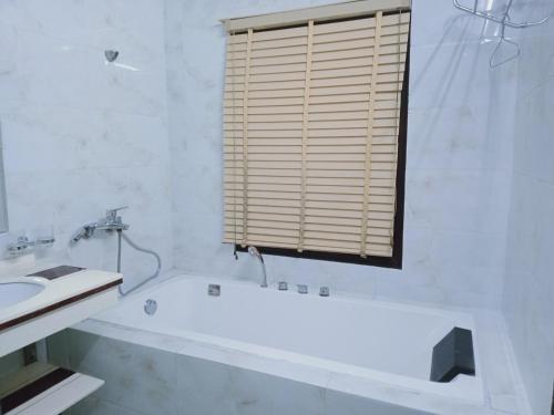 a bathroom with a tub and a sink and a window at Paloma Hotel Quan Lan in Quan Lạn