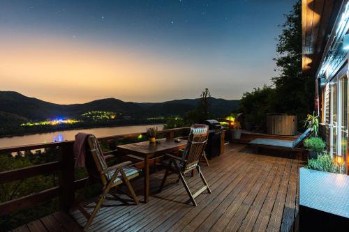 a wooden deck with a table and chairs at night at Sherpa Pihenőház in Nagymaros