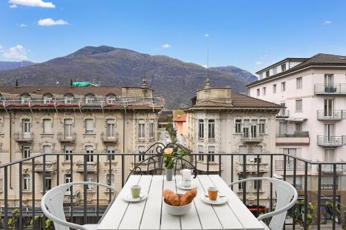 a white table and chairs on a balcony with buildings at Bellinzona Center in Bellinzona
