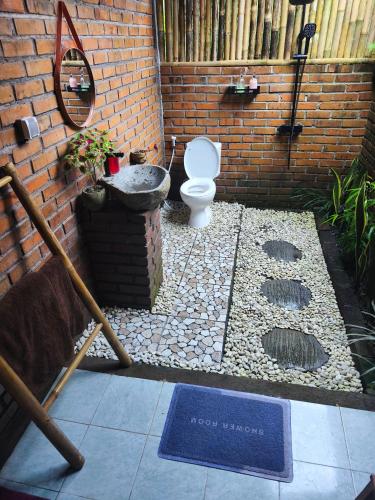 a bathroom with a toilet in a brick wall at Tuka Cabins in Jatiluwih