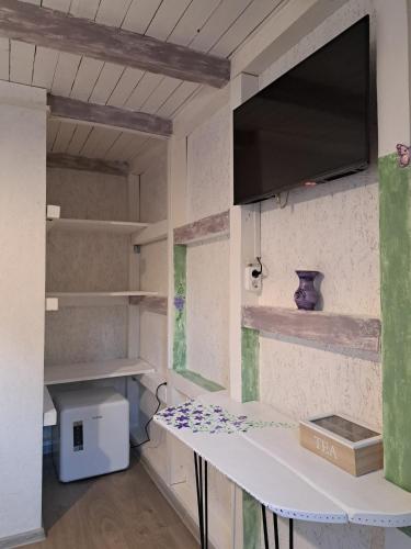 a room with a table and a tv on a wall at Căsuța Vesela in Cernişoara