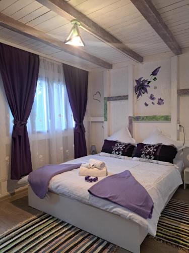 a bedroom with a large bed with purple curtains at Căsuța Vesela in Cernişoara