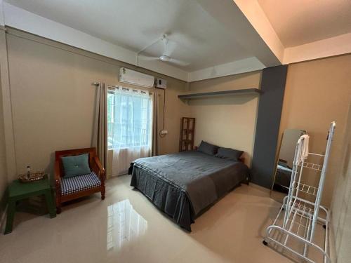 a bedroom with a bed and a chair and a window at Aika Homestay in Pāsighāt