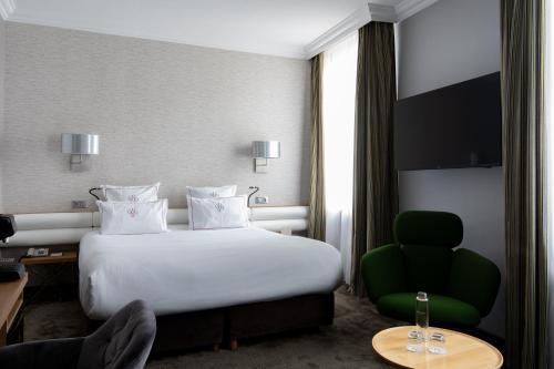 a hotel room with a bed and a green chair at Chapeau Rouge par William Frachot - Hôtel Espace Bien-être & Restaurant étoilé in Dijon