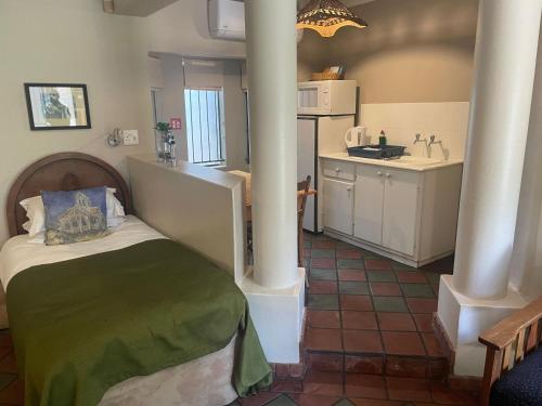 a small room with a bed and a kitchen at Dias Guest House in Bloemfontein