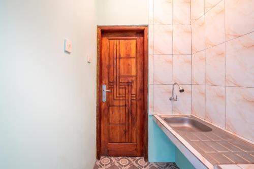a bathroom with a wooden door and a sink at Villa Malakai By ARBA in Palayangan